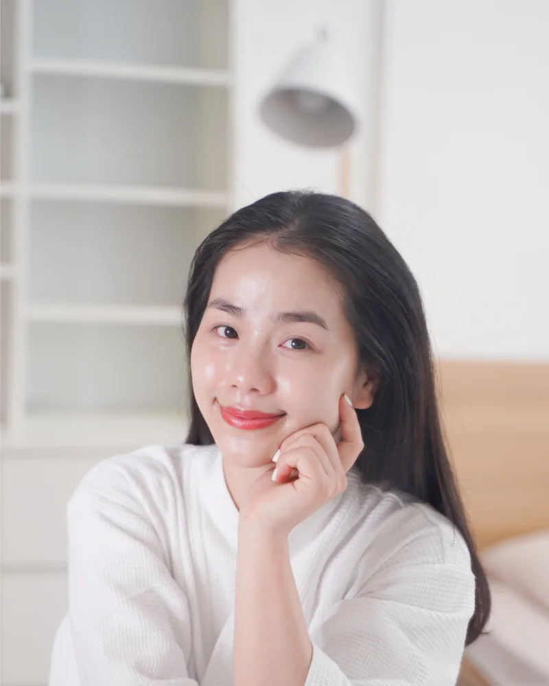 Quin ngồi ở bàn trang điểm, để mặt mộc, ánh sáng tự nhiên